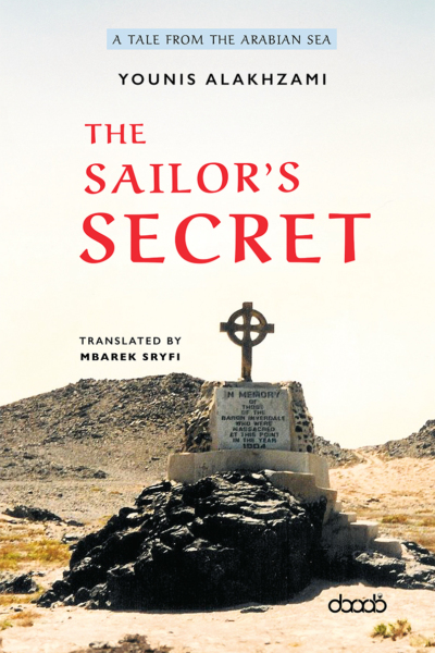 Book cover of The Sailor’s Secret by Younis Alakhzami, subtitled “A Tale from the Arabian Sea” and translated by Mbarek Sryfi. The image features a remote desert landscape with a stone memorial topped by a Celtic-style cross, commemorating sailors massacred in 1904. The title is in bold red letters, and the DarArab logo appears at the bottom.
